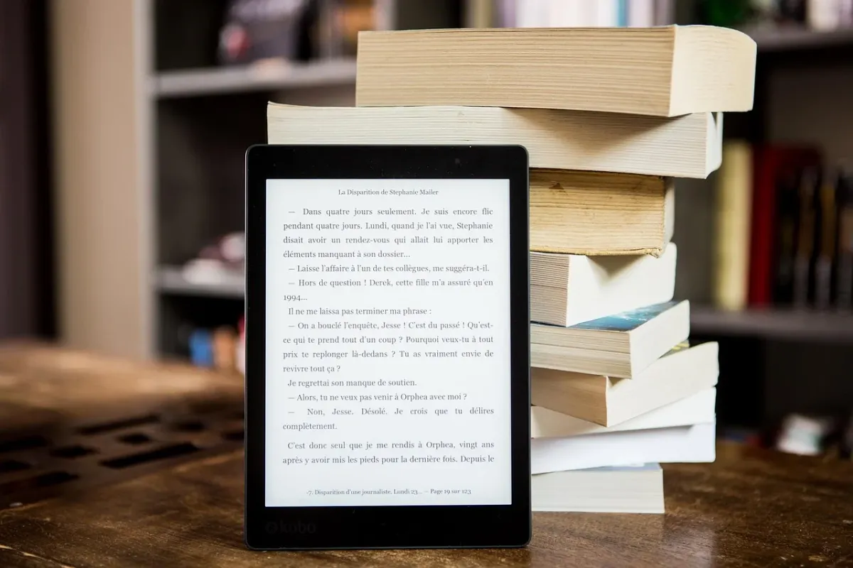 Czytnik e-booków z zestawem książek, symbolizujący przygotowanie do nauki i radość z czytania w nowym roku szkolnym.